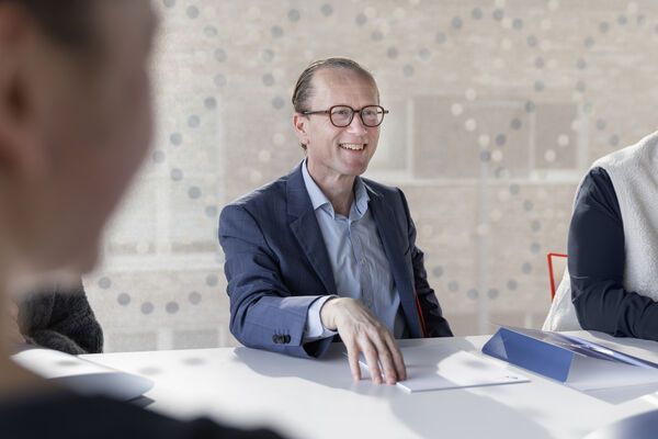 Olivier Beyls lacht ontspannen aan de vergadertafel tijdens een overleg